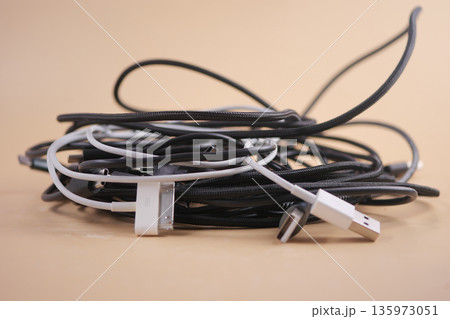 Cables and chargers tangled together on a flat surface Cables and chargers tangled together on a flat surface 135973051