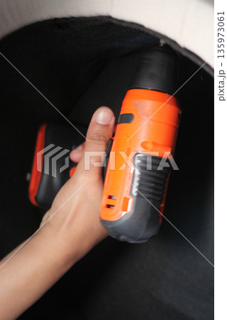 Worker uses drill to fix a surface in a workshop 135973061