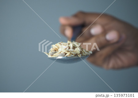 Spoon holding oats in hand ready for breakfast preparation 135973101