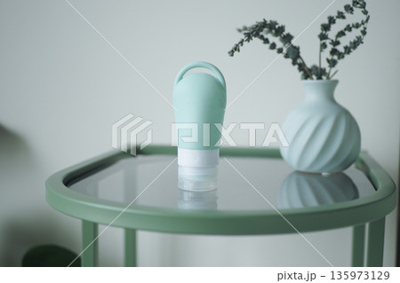Soft green bottle on table with vase and plants Soft green bottle on table with vase and plants 135973129