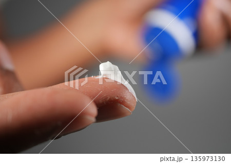 Applying cream to a finger during a skincare routine 135973130