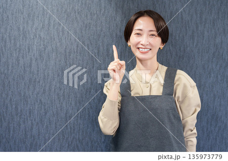 エプロンを着た指差す女性店員 エプロンを着た指差す女性店員 135973779
