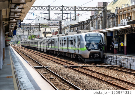 A local train (EMU900 series) is stopped on the platform of the Hsinchu Railway Station. It was the oldest station in Taiwan, now listed as a national monument. 135974333