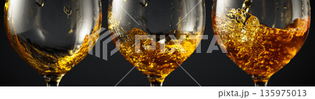 White wine of rich amber color being poured into a glass. 135975013