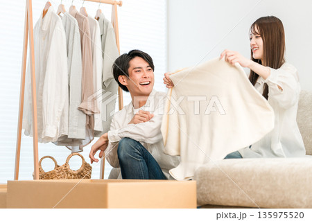 家のリビングで衣類を整理整頓,衣替えする若いアジア人カップル,夫婦 家のリビングで衣類を整理整頓,衣替えする若いアジア人カップル,夫婦 135975520
