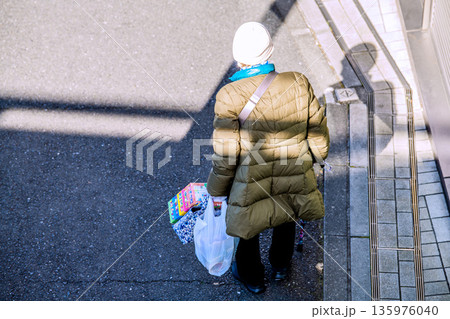 日本の横浜都市景観光と“陰”…高齢化社会　杖の高齢女性（マスク姿）。買い物帰り、左手は手袋… 135976040