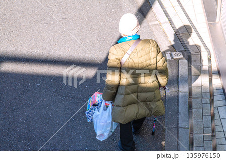 日本の横浜都市景観光と“陰”…高齢化社会　杖の高齢女性（マスク姿）。買い物帰り、左手は手袋… 135976150