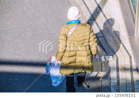 日本の横浜都市景観光と“陰”…高齢化社会　杖の高齢女性（マスク姿）。買い物帰り、左手は手袋… 135976151
