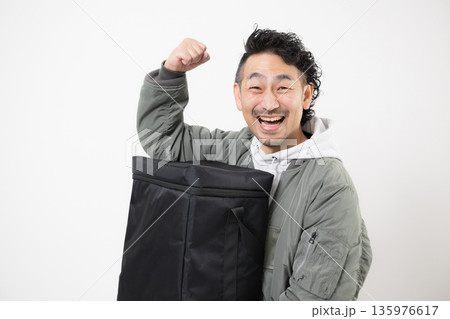 笑顔の配達員がデリバリー用配達バッグを持つフードデリバリー、出前宅配サービスの仕事イメージ 135976617