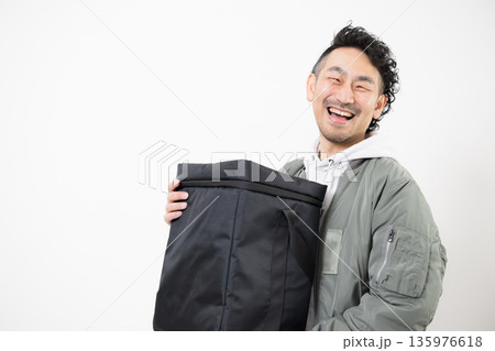 笑顔の配達員がデリバリー用配達バッグを持つフードデリバリー、出前宅配サービスの仕事イメージ 笑顔の配達員がデリバリー用配達バッグを持つフードデリバリー、出前宅配サービスの仕事イメージ 135976618