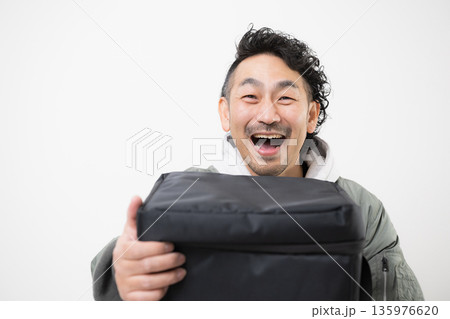 笑顔の配達員がデリバリー用配達バッグを持つフードデリバリー、出前宅配サービスの仕事イメージ 135976620