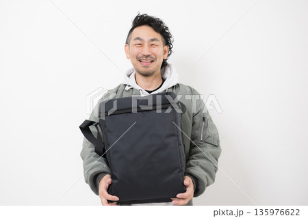 笑顔の配達員がデリバリー用配達バッグを持つフードデリバリー、出前宅配サービスの仕事イメージ 135976622