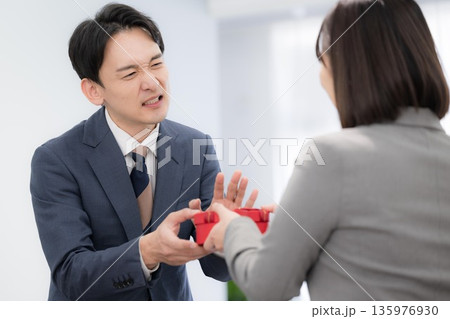 オフィスでプレゼンとやバレンタインに困る、戸惑うので断る男性社員のビジネスシーン オフィスでプレゼンとやバレンタインに困る、戸惑うので断る男性社員のビジネスシーン 135976930