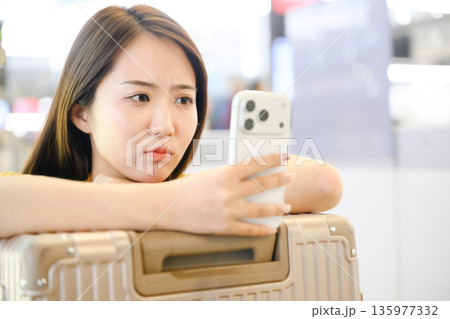 空港でスマホを見る女性 ■撮影協力:関西国際空港(KIX) 空港でスマホを見る女性 ■撮影協力:関西国際空港(KIX) 135977332