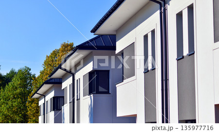 Terraced family homes in newly developed housing estate. The real estate market in the suburbs. New single family houses in a new development area. Residential homes with modern facade. Terraced family homes in newly developed housing estate. The real estate market in the suburbs. New single family houses in a new development area. Residential homes with modern facade. 135977716