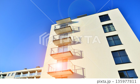 Apartment residential house and home facade architecture and outdoor facilities. Blue sky on the background. Sunlight in sunrise. 135977811