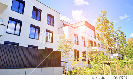 Modern architecture of urban residential apartment buildings on a sunny day. Low-rise apartment buildings with large windows and extensive terraces. White facade of a modern apartment building. Modern architecture of urban residential apartment buildings on a sunny day. Low-rise apartment buildings with large windows and extensive terraces. White facade of a modern apartment building. 135978792