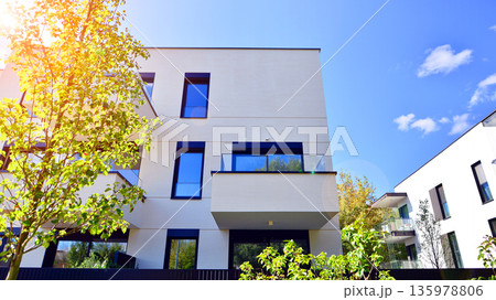 Modern architecture of urban residential apartment buildings on a sunny day. Low-rise apartment buildings with large windows and extensive terraces. White facade of a modern apartment building. Modern architecture of urban residential apartment buildings on a sunny day. Low-rise apartment buildings with large windows and extensive terraces. White facade of a modern apartment building. 135978806