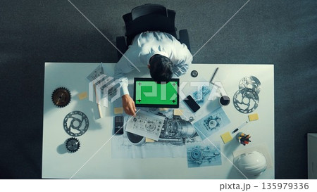 Top view of engineer look at mobile phone while working on tablet. Alimentation. 135979336