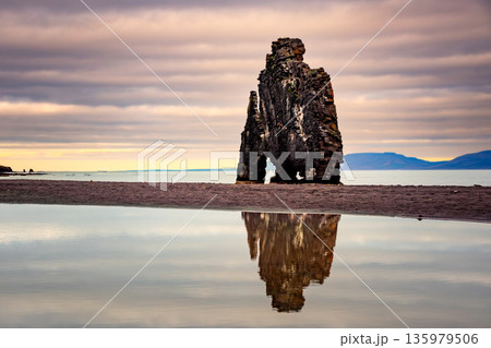 Hvitserkur Rock stands majestically in Iceland, surrounded by tranquil waters. The scene captures the interplay of light and clouds at sunset, showcasing Iceland's stunning natural beauty. 135979506