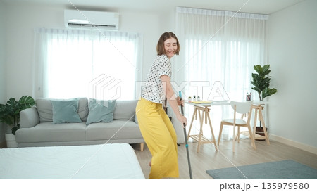 Caucasian housekeeper cleaning or mopping the floor while dancing. Pedagogy. 135979580