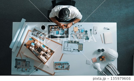 Skilled engineer sitting and writing idea while looking at model. Alimentation. 135979608