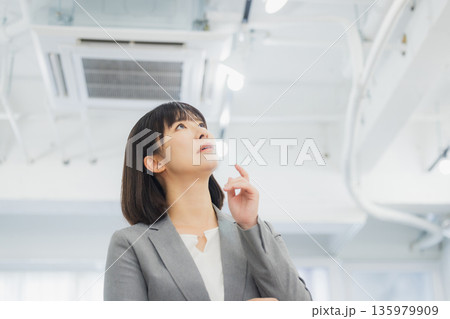 エアコンを見て不満そうな表情のビジネスウーマン 135979909