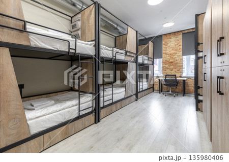Modern loft dormitory with rows of bunk beds and wooden lockers Modern loft dormitory with rows of bunk beds and wooden lockers 135980406