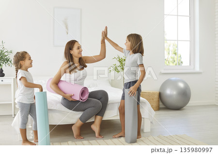 Young mother giving high five with children after morning workout at home 135980997