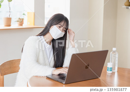 体調不良でも自宅でパソコンを操作する女性 体調不良でも自宅でパソコンを操作する女性 135981877