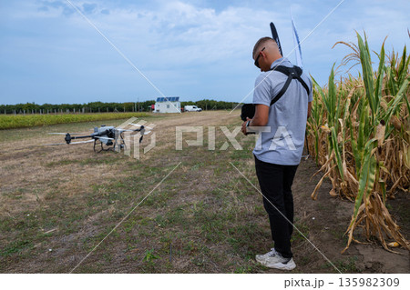 Drone Pilot Checks Camera Drone in a Cornfield for Agricultural Aerial Filming and Farming Operations Drone Pilot Checks Camera Drone in a Cornfield for Agricultural Aerial Filming and Farming Operations 135982309