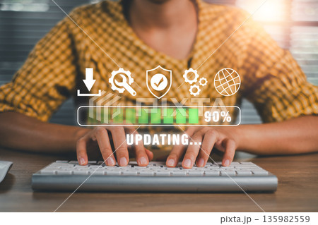 Close-up of a woman updating software on a computer, showing progress bar and security icons, symbolizing technology and cybersecurity. Close-up of a woman updating software on a computer, showing progress bar and security icons, symbolizing technology and cybersecurity. 135982559