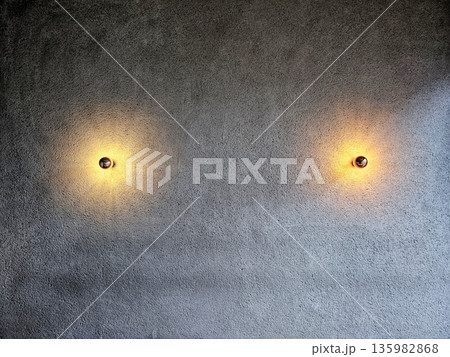 Two Modern Wall Sconces Illuminating a Textured Concrete Wall. Two Modern Wall Sconces Illuminating a Textured Concrete Wall. 135982868