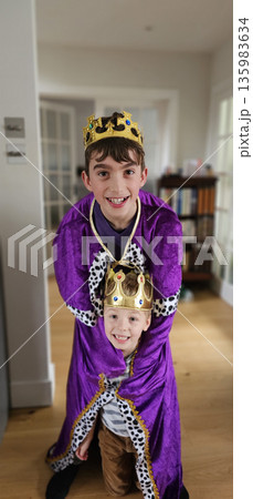 Two smiling children indoors wearing gold crowns and purple royal costumes Two smiling children indoors wearing gold crowns and purple royal costumes 135983634