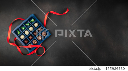 Luxury chocolate gift box with assorted pralines and red ribbon on dark background Luxury chocolate gift box with assorted pralines and red ribbon on dark background 135986380