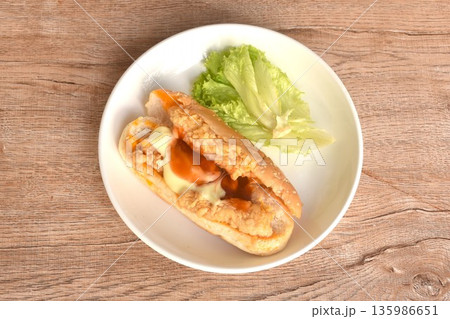 hot dog stuffed crispy fried chicken with lettuce dressing ketchup and mayonnaise on dish hot dog stuffed crispy fried chicken with lettuce dressing ketchup and mayonnaise on dish 135986651