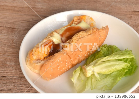 hot dog stuffed crispy fried chicken with lettuce dressing ketchup and mayonnaise on dish hot dog stuffed crispy fried chicken with lettuce dressing ketchup and mayonnaise on dish 135986652