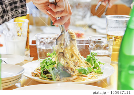湯気が立ち上るキノコのパスタをトングで豪快に持ち上げるシズル感のある写真 135987111