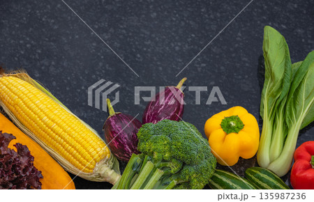 Colorful assortment of fresh vegetables on a dark background with empty space in the center Colorful assortment of fresh vegetables on a dark background with empty space in the center 135987236