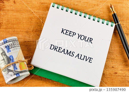 A white spiral notebook with KEEP YOUR DREAMS ALIVE sits on a wooden surface A white spiral notebook with KEEP YOUR DREAMS ALIVE sits on a wooden surface 135987490