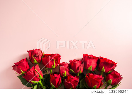 Valentine's Day background. Red roses flower bouquet over pink background. Abstract flat lay. Festive greeting card. Valentine's Day background. Red roses flower bouquet over pink background. Abstract flat lay. Festive greeting card. 135990244