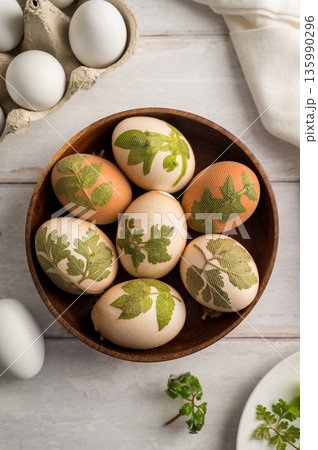 DIY Easter eggs with natural leaves, creating patterns on eggs using plants. Eco friendly colouring easter eggs 135990296