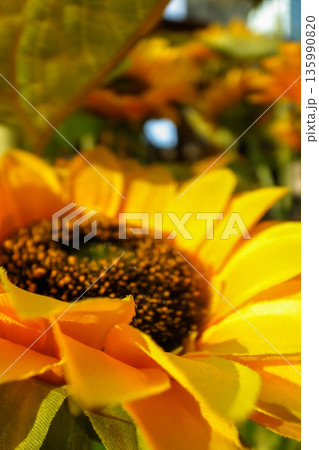 Close-up of artificial sunflower in the outdoors with sunlight. Artificial sunflower for decoration. 135990820
