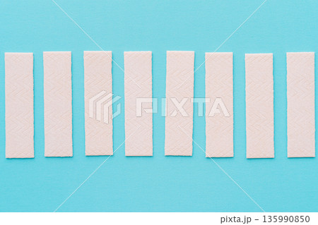 Chewing gum sticks aligned on turquoise background, minimal composition 135990850