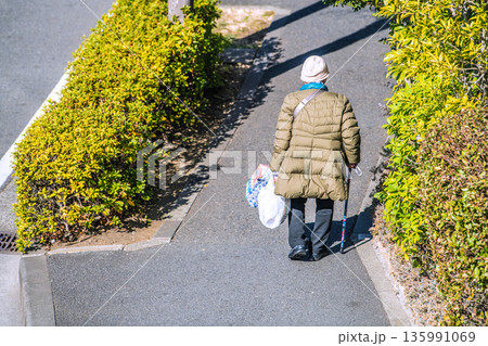 日本の横浜都市景観光と“陰”…高齢化社会　杖の高齢女性（マスク姿）。買い物帰り、左手は手袋… 135991069