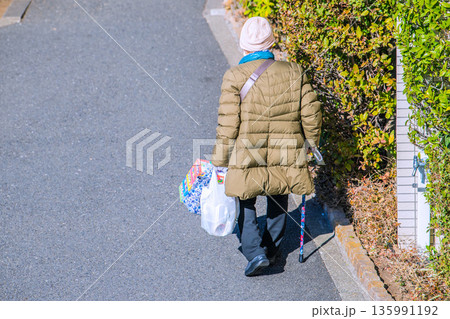 日本の横浜都市景観光と“陰”…高齢化社会　杖の高齢女性（マスク姿）。買い物帰り、左手は手袋… 135991192
