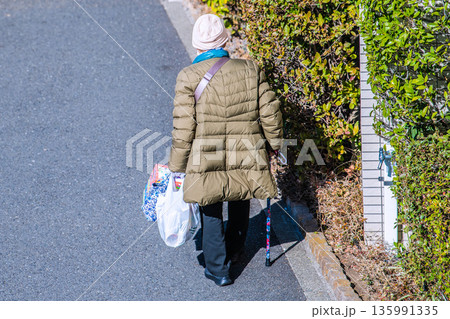 日本の横浜都市景観光と“陰”…高齢化社会　杖の高齢女性（マスク姿）。買い物帰り、左手は手袋… 135991335