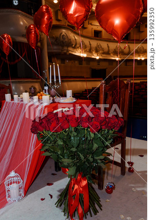 Romantic Valentine's Day Dinner Setup with Red Roses and Heart Balloons in a Grand Theater Venue Romantic Valentine's Day Dinner Setup with Red Roses and Heart Balloons in a Grand Theater Venue 135992350