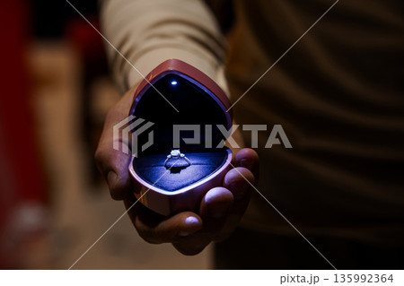 Romantic Proposal Moment with Diamond Ring in Heart-Shaped Box Held by Hand in Dark Ambient Lighting Romantic Proposal Moment with Diamond Ring in Heart-Shaped Box Held by Hand in Dark Ambient Lighting 135992364