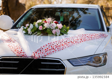 White Wedding Car Decorated with Pink and White Flowers and Heart-Printed Ribbon on Hood 135992384